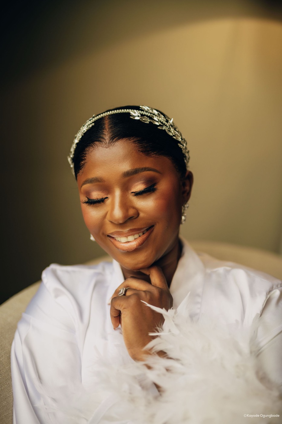A bride in a white feathered gown, photographed in soft window light